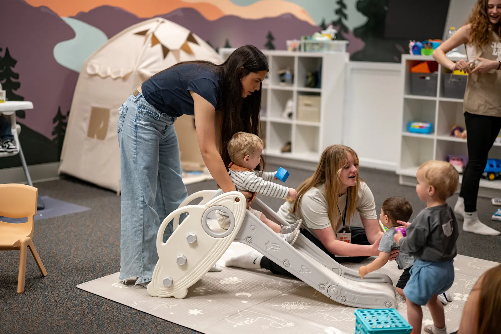 Sun City Kids volunteers playing with toddlers in a bright classroom