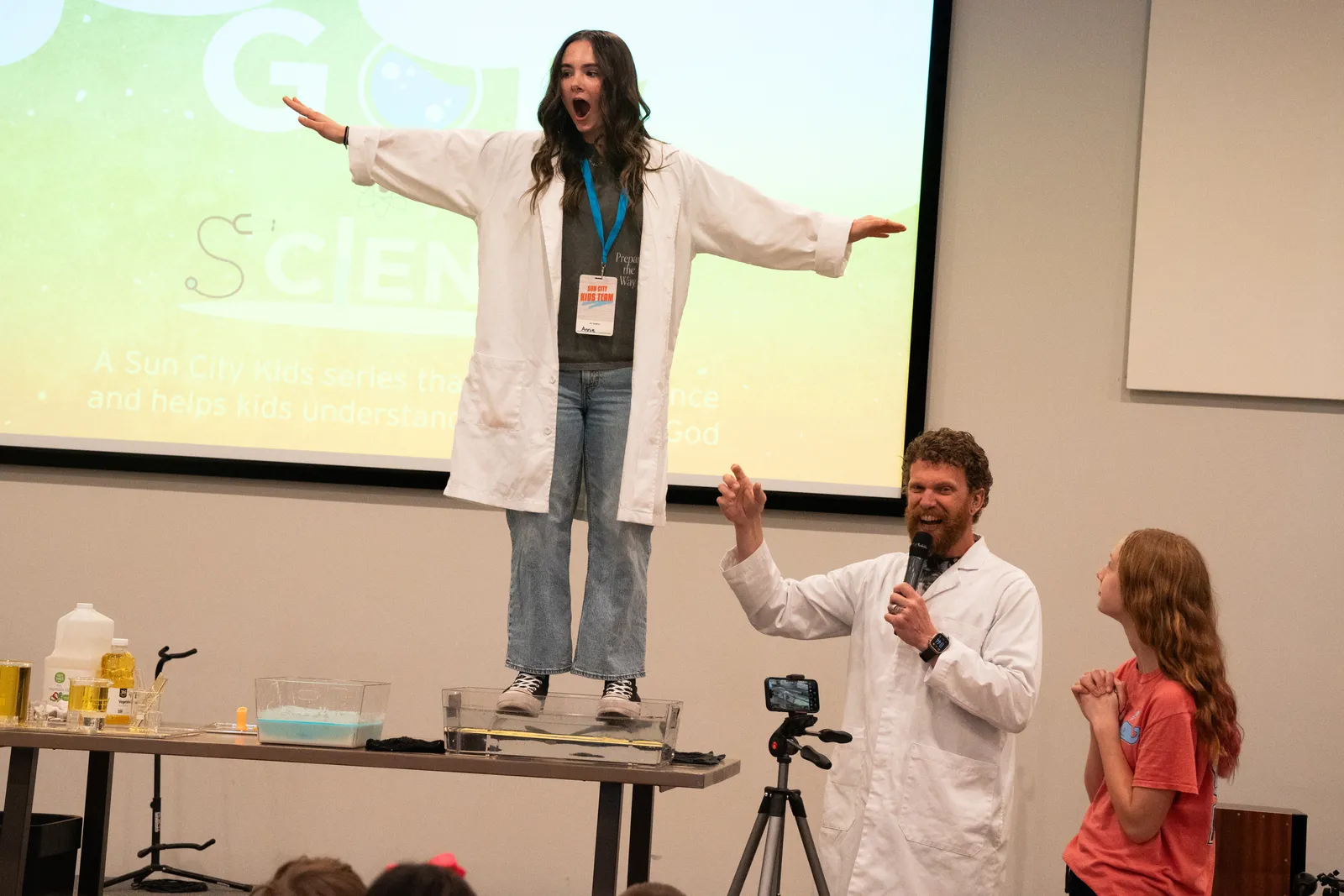 An energetic science-style lesson on stage at Sun City Kids